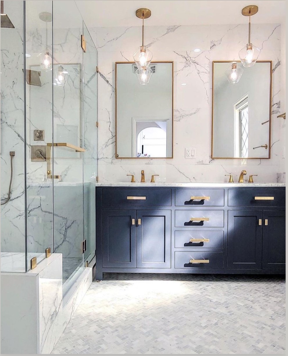 Coordinated marble-look bathroom with custom glass shower, navy vanity, and warm metal fixtures