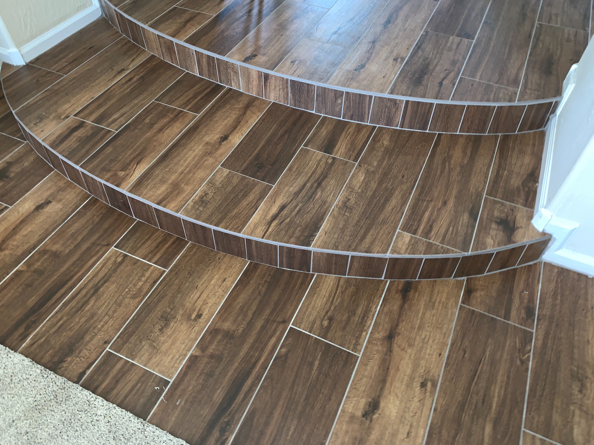 Curved custom staircase finished with wood-look tile and hand-cut edges