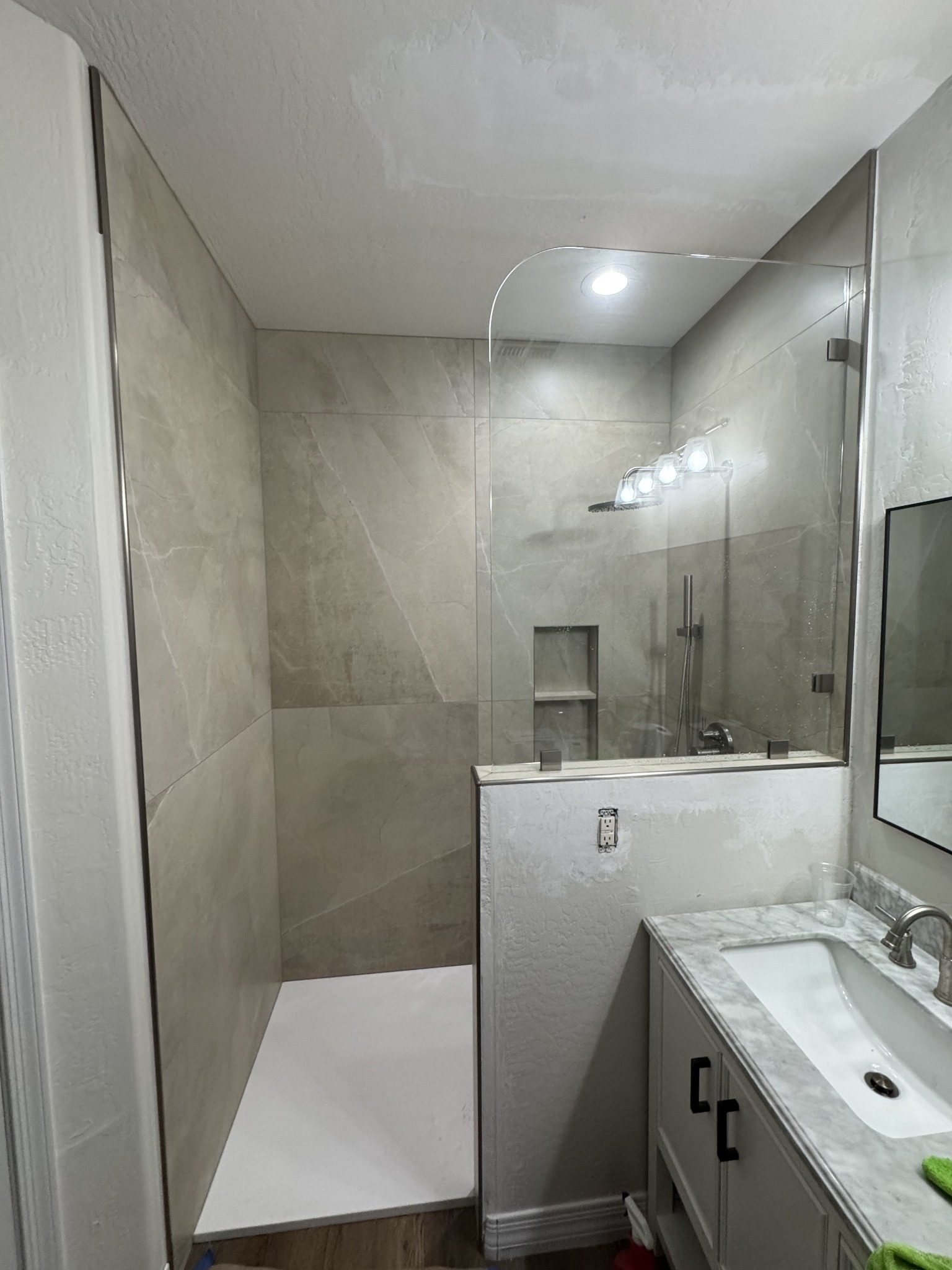 Completed bathroom remodel with tiled shower, custom glass, and vanity