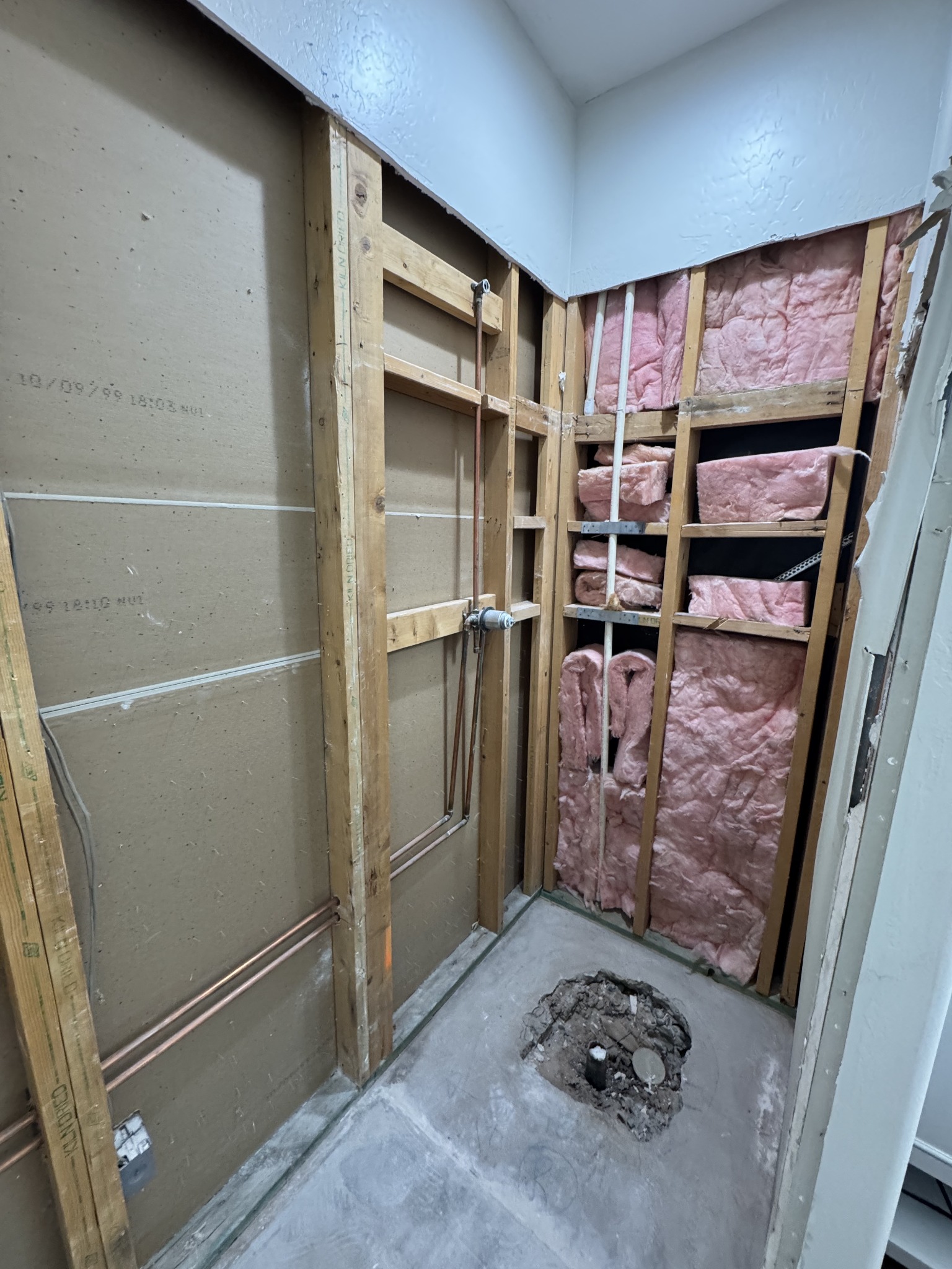 Shower remodeling in progress with walls opened and plumbing exposed